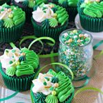 Irish Cream chocolate cupcakes topped with white and green buttercream piping and shamrock sprinkle mix