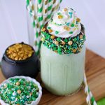 Green mint chocolate chip milkshake with chocolate coated sprinkle rim and whipped cream