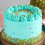 PIneapple cake with pineapple curd, teal frosting and tropical sprinkle mix