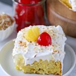 Easy Piña Colada Poke Cake - pineapple cake, coconut cream pudding, whipped topping, pineapple chunks and maraschino cherries