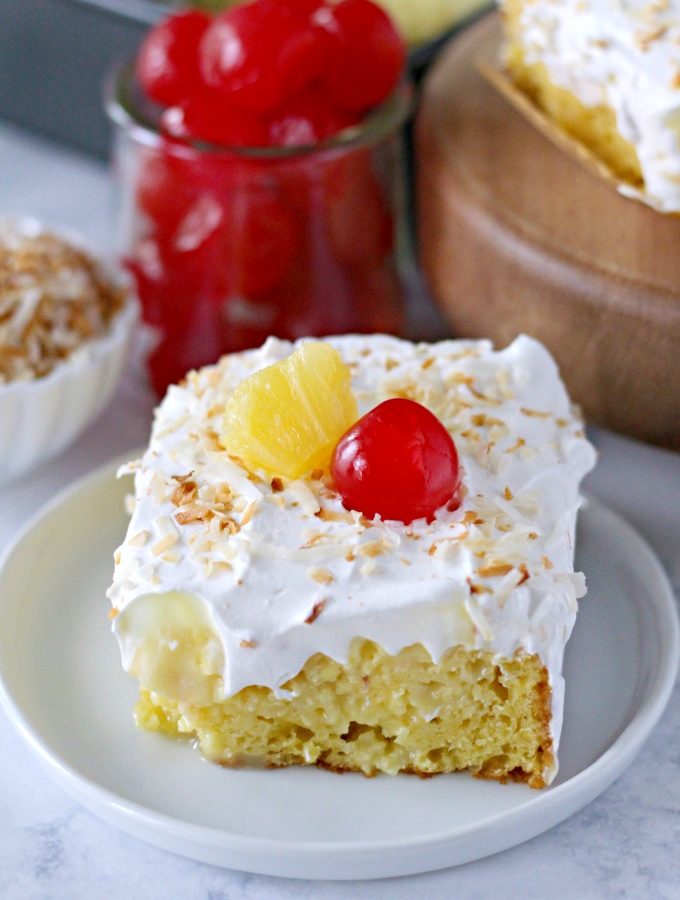 Easy Piña Colada Poke Cake - pineapple cake, coconut cream pudding, whipped topping, pineapple chunks and maraschino cherries